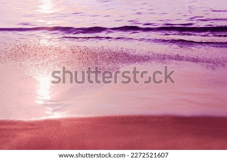 Toned purple photo of beach. Marine background. Sea coast at sunset. Glare of setting sun on wet sand