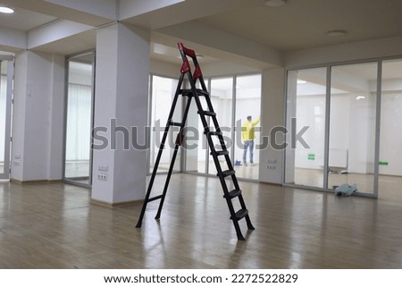 High ladder standing in center of empty office. Rent new commercial real estate, office renovation and improvement concept. Royalty-Free Stock Photo #2272522829