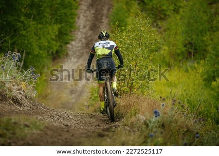 back male athlete on mountain bike ride forest trail. dirt on feet and body. cross-country cycling competition Royalty-Free Stock Photo #2272525117