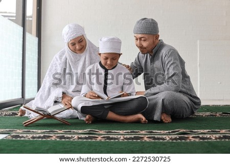 Traditional muslim family parents with children reading Quran and praying together during a ramadan feast at the mosque Royalty-Free Stock Photo #2272530725