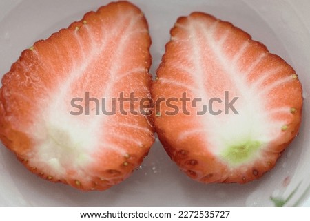A cross section cut in half of a bright red strawberry that looks delicious