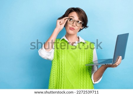 Photo of clever developer it company worker young woman wear green vest touch glasses hold netbook mind look mockup isolated on blue color background