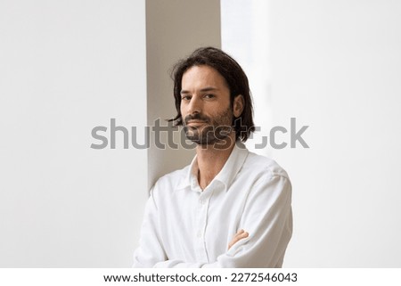 portrait of a smiling 30 year old man looking at the camera. He is standing in his office. Businessman or office worker.
