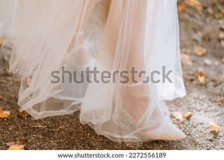 Close up of bride walking on sidewalk with fall leaves