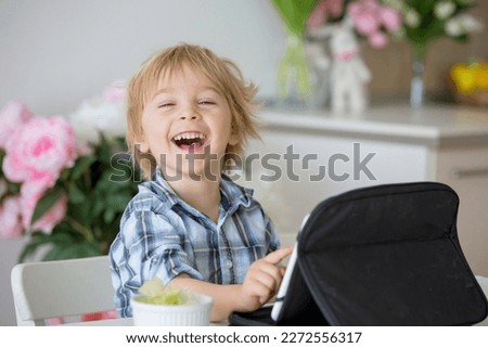 Little toddler child, blond boy, licking lollipop at home while watching movie on tablet Royalty-Free Stock Photo #2272556317