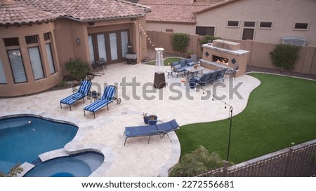 An aerial view of a desert landscaped backyard in Arizona featuring a travertine pool deck and fireplace. Royalty-Free Stock Photo #2272556681