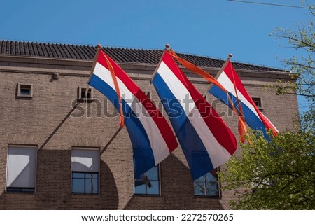 three times a Dutch flag in red white blue with an orange ribbon to indicate that it is someone from the royal family's birthday