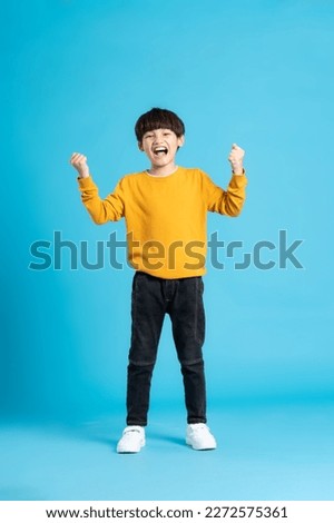 full body image of asian boy posing on blue background Royalty-Free Stock Photo #2272575361