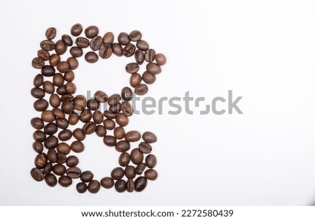 B is a capital letter of the English alphabet made up of natural roasted coffee beans that lie on a white background. Plenty of space to put text or pictures, top view and studio photography.