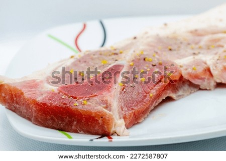 raw pork fillet in a white platter on a white background