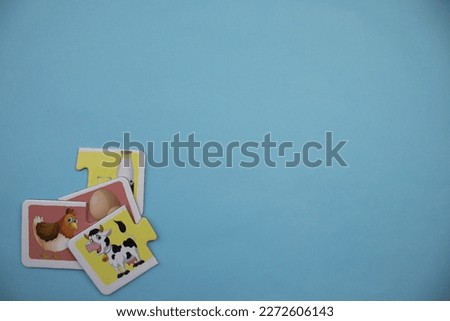 Cow picture puzzle in black and white, knowledge puzzles with pictures of brown chicken, white egg, black and white cow and milk bottle placed on the left over blue background.