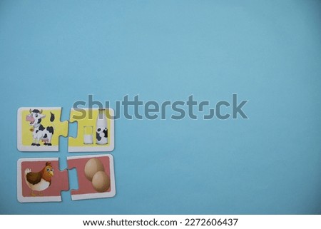 Animal picture puzzles, knowledge puzzles with pictures of brown chicken, white egg, black and white colored cow and milk bottle placed on the left over blue background.