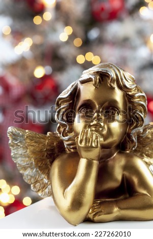 Golden angel figure close up christmas tree in background