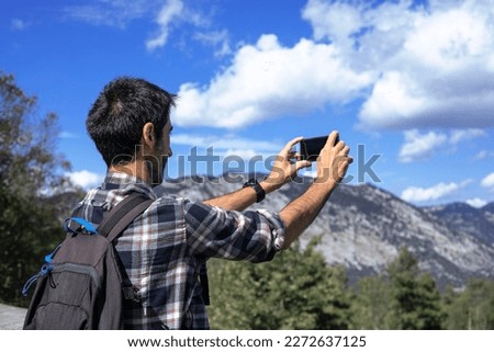 Hiker with backpack takes photo whit his cellular of the mountains of the Urkiola Natural Par in the Basque Country, Spain.