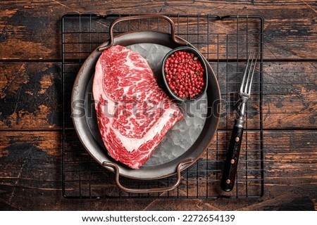 Raw wagyu rib eye beef meat steak in steel tray. Wooden background. Top view. Royalty-Free Stock Photo #2272654139