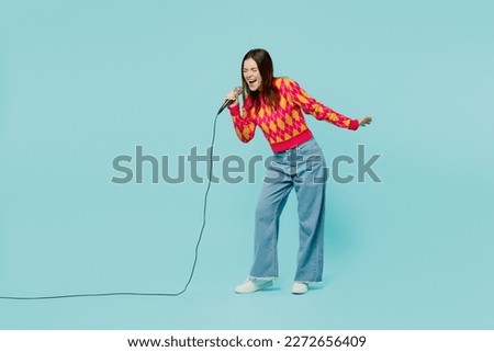 Full body young caucasian woman wear bright casual clothes sing song in microphone at karaoke club spread hand isolated on plain pastel light blue cyan background studio portrait. Lifestyle concept Royalty-Free Stock Photo #2272656409