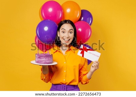 Happy fun young woman wears casual clothes celebrating near balloons hold cake gift certificate coupon voucher card for store isolated on plain yellow background. Birthday 8 14 holiday party concept