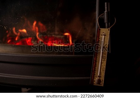 Burning fireplace and old thermometer. Heating temperature in room, heating with wood. Heat transfer of different types of wood.
