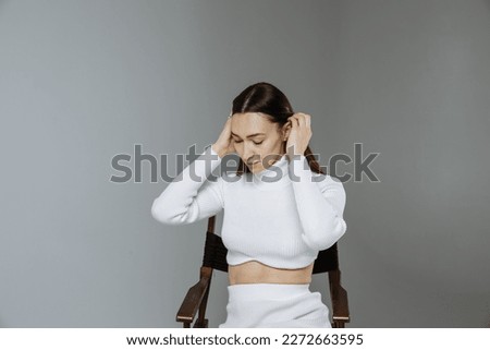 A girl in white clothes on a gray background of a photo studio