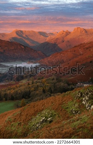 Beautiful Lake District sunrise with Autumn colours and golden light on Langdale Pikes mountains. 