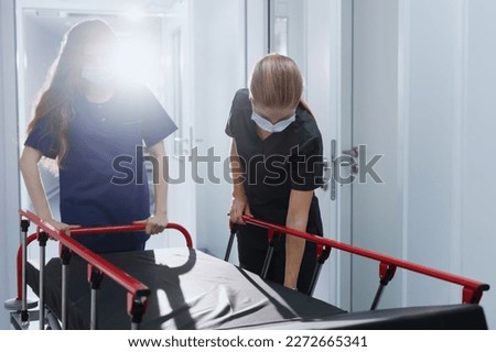 Two nurses roll an empty hospital gurney down the corridor. Emergency call. Royalty-Free Stock Photo #2272665341
