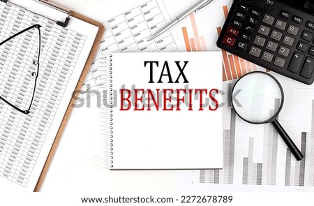 TAX BENEFITS text on a notebook with clipboard and calculator on a chart background