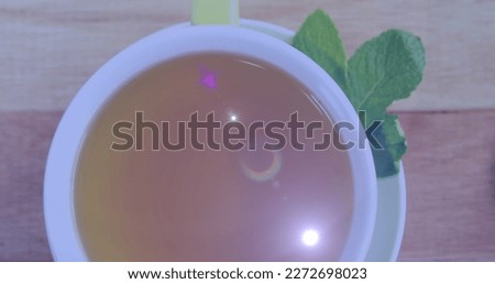 Image of light spots over cup of tea on table. national relaxation day and celebration concept digitally generated image.