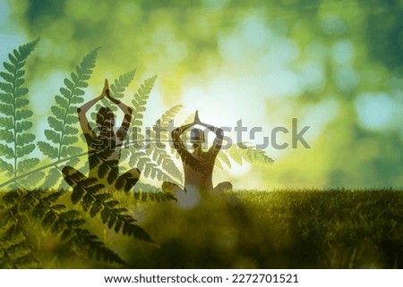 Man woman couple practices yoga and meditates in green nature setting. Concept of meditation, dreaming, wellbeing and healthy lifestyle Royalty-Free Stock Photo #2272701521