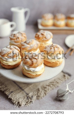 Cream puffs filled with vanilla cream and whipped cream on a white plate Royalty-Free Stock Photo #2272708793