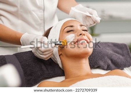 Shot of a beautiful young woman getting a facial mask treatment at the beauty salon. Royalty-Free Stock Photo #2272709339