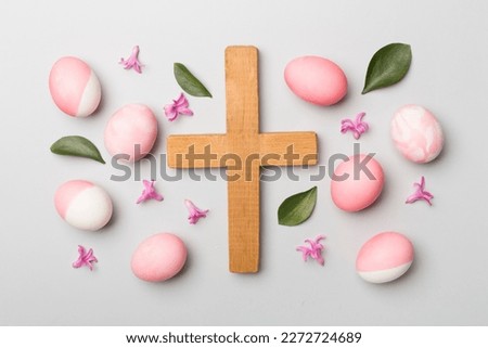 Pink Easter eggs with cross and leaves on color background, top view