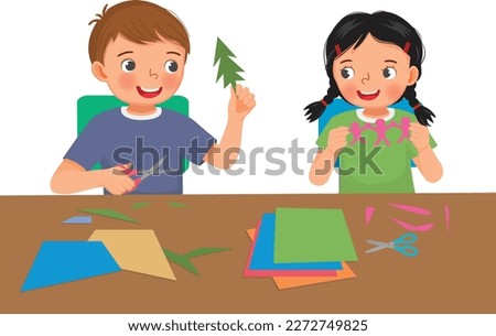 Cute little kids boy and girl cutting colored paper with scissors making paper cut art craft