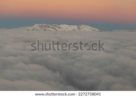 Peaks of snowy mountains over gray clouds in the dawn sky