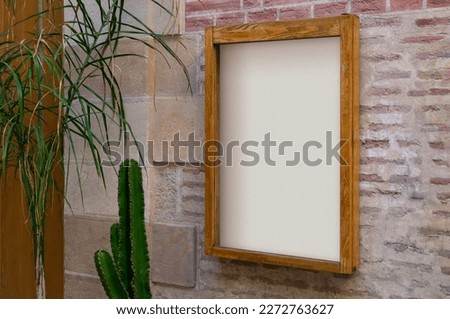 White poster in a wooden frame on a stone wall
