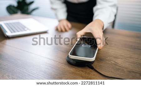 Charging mobile phone battery with wireless charging device in the table. Smartphone charging on a charging pad. Mobile phone near wireless charger Modern lifestyle technology 