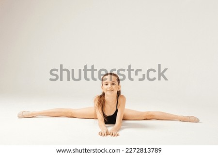 The girl does gymnastics raises her leg up and smiles.