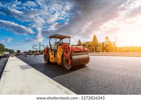 Construction site is laying new asphalt pavement, road construction workers and road construction machinery scene. Highway construction site scene. Royalty-Free Stock Photo #2272826343