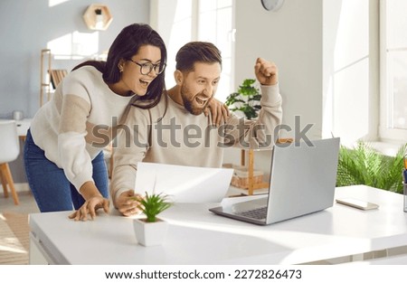 Family couple getting excited about success when they get email with excellent job offer. Happy young man and woman reading good news and looking at laptop computer with very excited face expressions Royalty-Free Stock Photo #2272826473