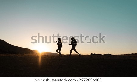 Running people over rough terrain. two girls train outdoors in a beautiful mountain landscape at sunset. silhouette of two girls during a hike in the mountains.