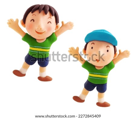 Two smiling boys with caps on and hands raised(This is a photo of a clay work)