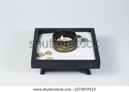 Burning tea candle on a wooden stand on a white background. little zen garden