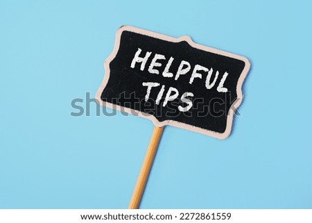 Helpful Tips - text on a small chalkboard on a blue background. Top view. Business, tips and tricks concept