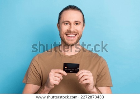 Portrait photo of cheerful happy young guy promoter demonstrate plastic monobank advertisement cashback service isolated on blue color background