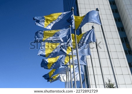 State flags of Bosnia and Herzegovina waving on the wind. Bosnia Herzegovina national flag blowing on flagpole in front of Parliament in Sarajevo.  Royalty-Free Stock Photo #2272892729