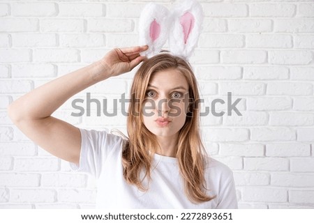 Spring holidays, Easter. Portrait of a happy woman in bunny ears on white brick wall background