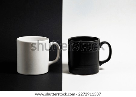White cup for coffee or tea on black background and black cup on white background, copy space, isolated  Royalty-Free Stock Photo #2272911537