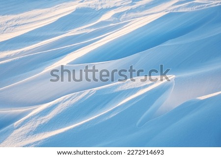Snow texture. Wind sculpted patterns on snow surface. Wind in the tundra and in the mountains on the surface of the snow sculpts patterns and ridges (sastrugi). Arctic, Polar region. Winter background Royalty-Free Stock Photo #2272914693