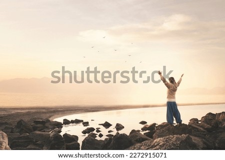 woman with arms outstretched takes a breath in front of a spectacular seascape Royalty-Free Stock Photo #2272915071