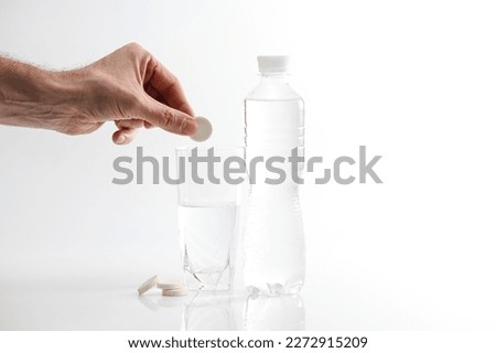 A hand holding effervescent soluble calcium tablet or vitamin C is placed in a glass of water. Health.The concept of a healthy lifestyle, prevention of vitamin deficiency. Isolated on white background
