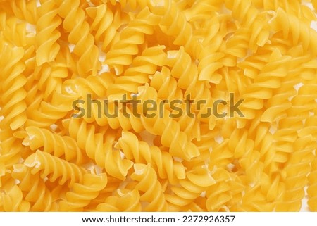 Background of raw hard pasta in the form of a spiral. Big pile of pasta top view. Free space for text and advertising. Italian cuisine in the form of pasta in the form of a spiral